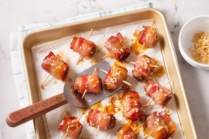 Baked Bacon Wrapped Sausage Bites in a tray with a serving ladle.