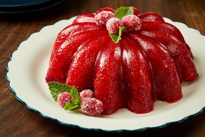 Table view shot of Molded Cranberry-Orange Salad; served on a platter; empty plates nearby; all set on a brown wooden surface;