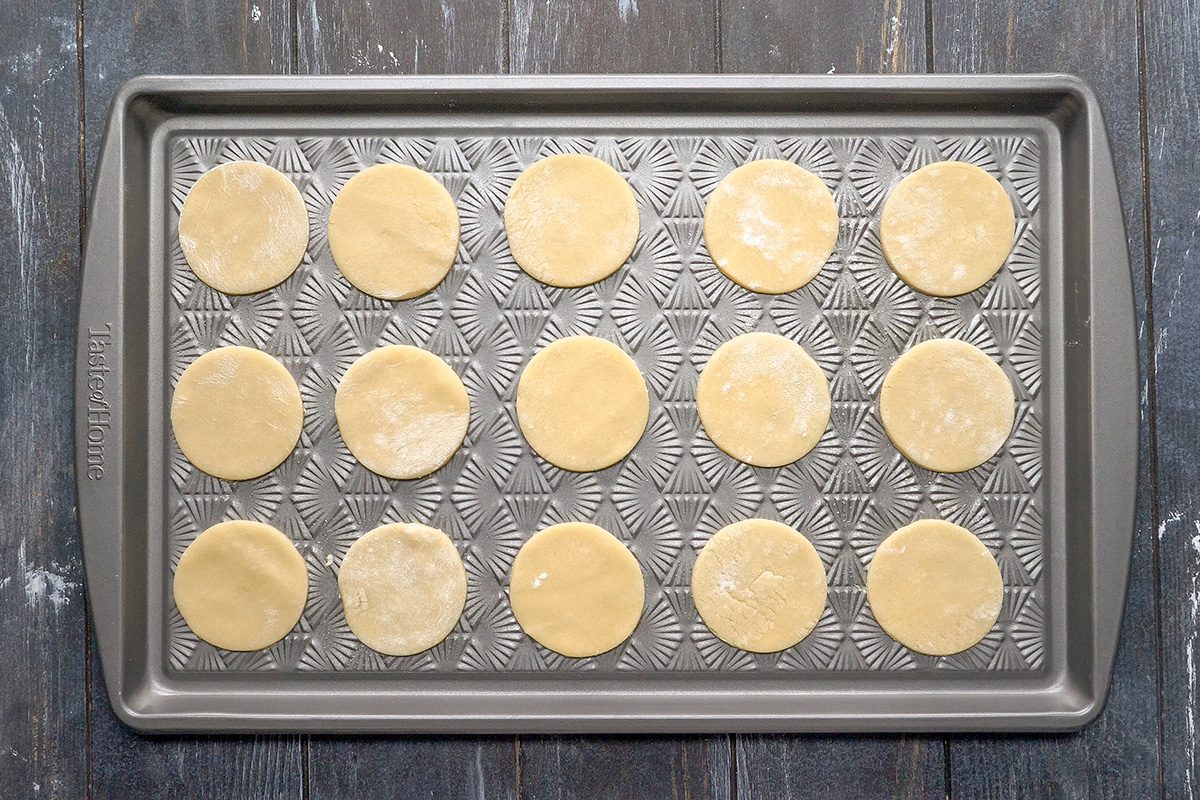 Overhead shot of a metal baking sheet holding fifteen evenly spaced, round, unbaked cookie dough discs