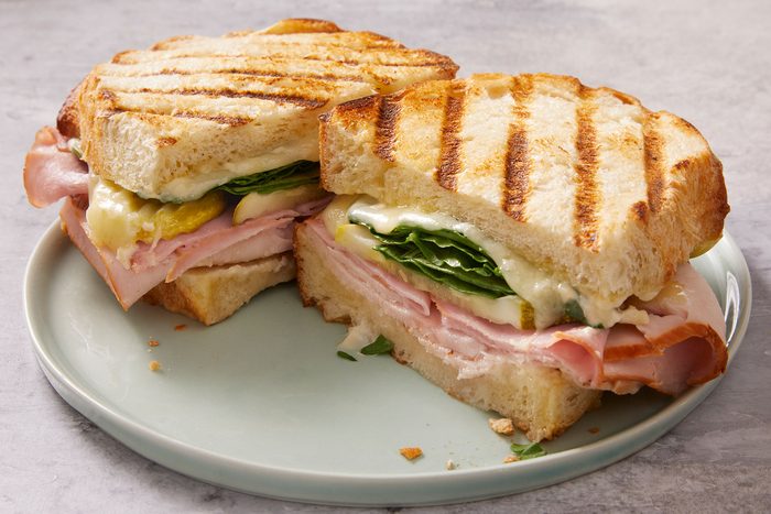Grilled cuban panini cut in two pieces and served in a plate.