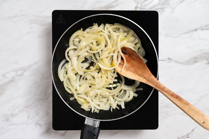 Overhead shot of the same skillet; saute onions in butter until tender; induction; all set on a white marble surface;