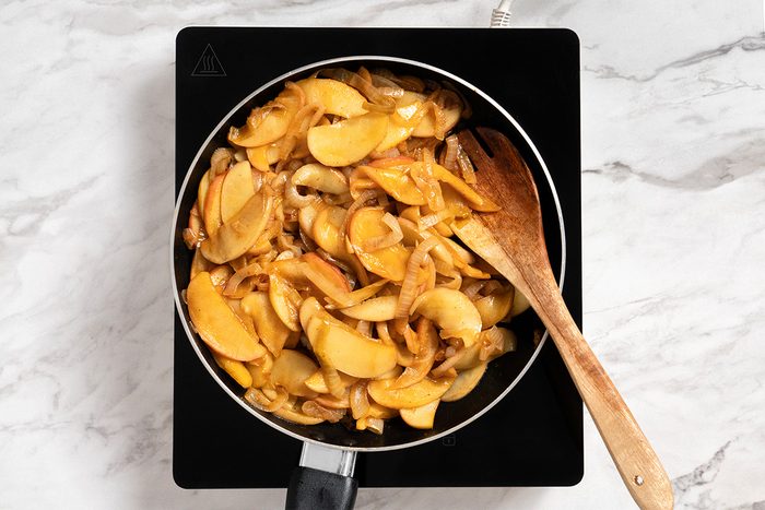 Overhead shot of uncover and simmer until apples are tender about 5 minutes longer; induction; all set on a white marble surface;