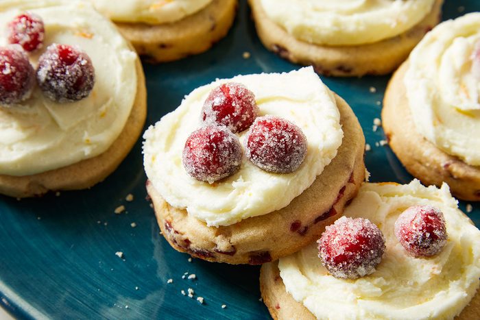 Close-up shot of Frosted Sugared Cranberry Cookies topped with sugared cranberries on a teal plate.