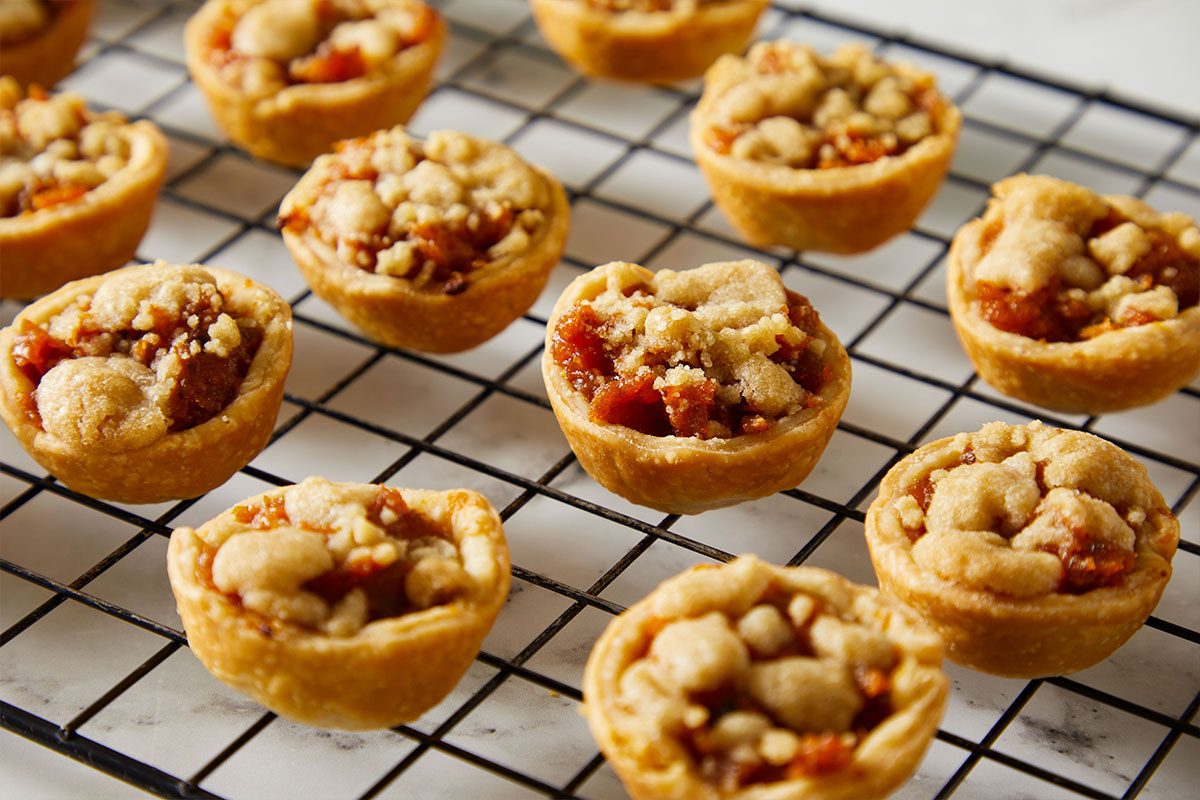 3/4 shot of golden Mini Sweet Potato Pies cooling on a wire rack.