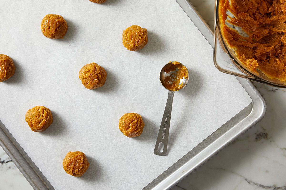 Overhead shot of unbaked peanut butter cookie dough balls arranged on a parchment-lined baking sheet