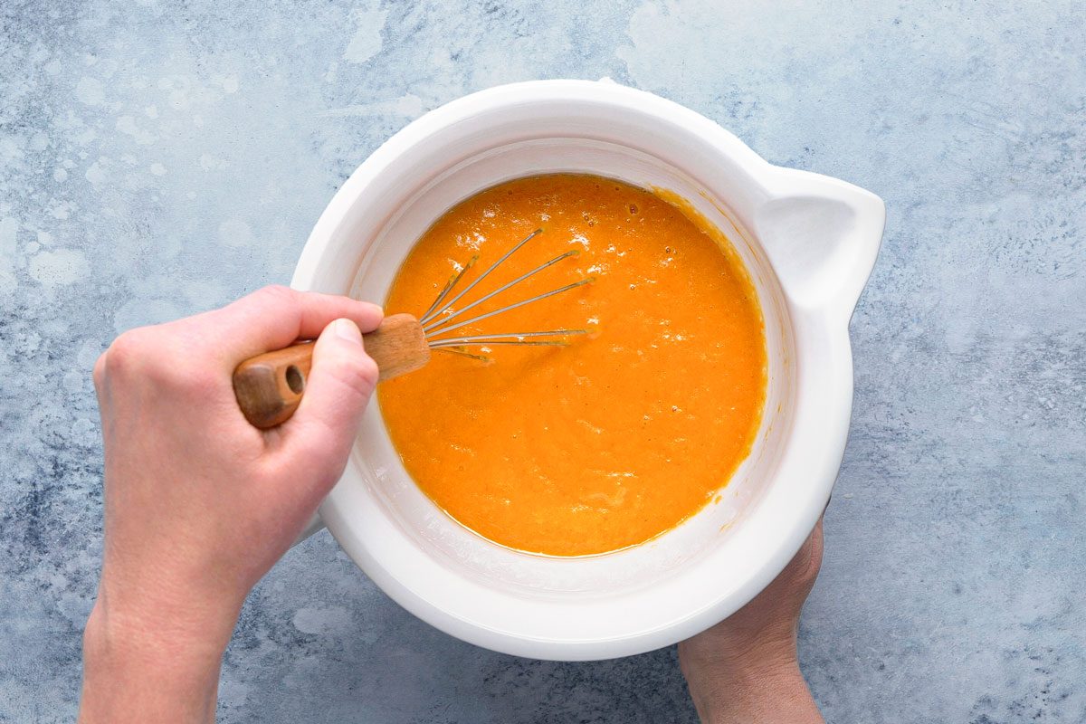 pumpkin puree, water, eggs and canola oil being whisked together in a bowl