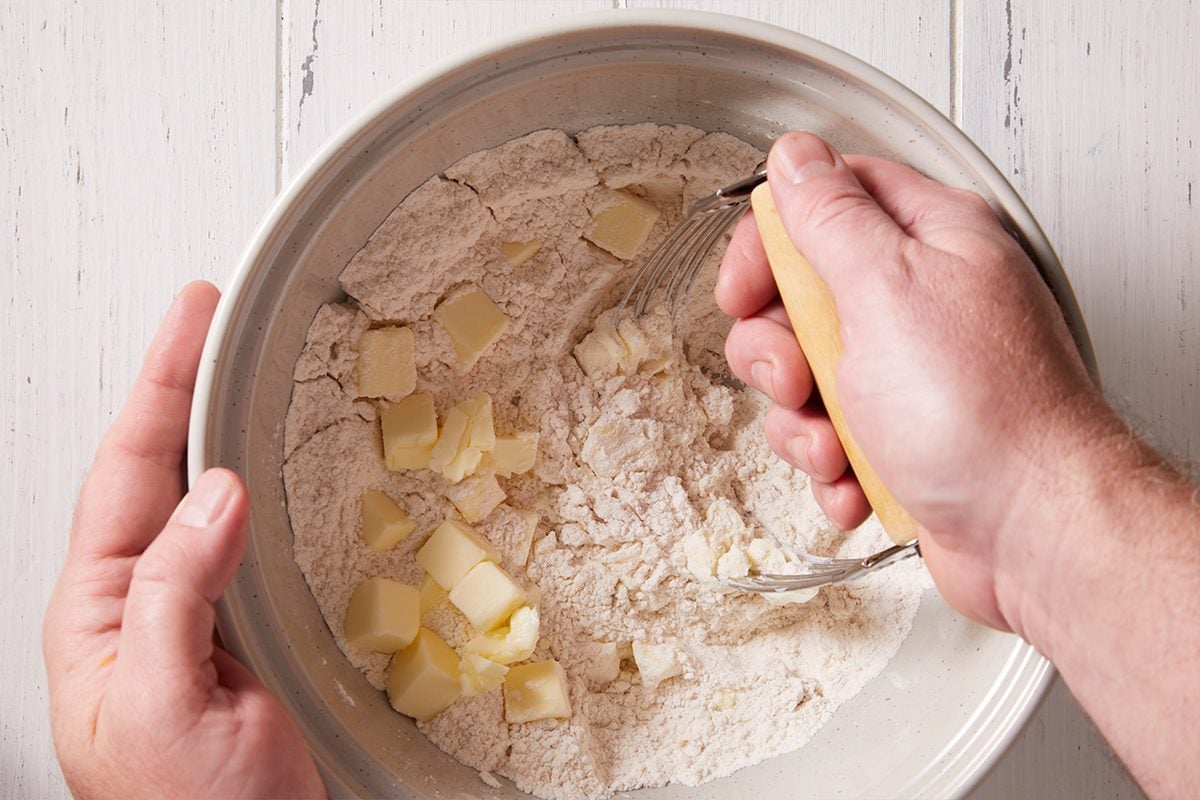 Adding butter cubes to the mixture for Pumpkin Biscuits