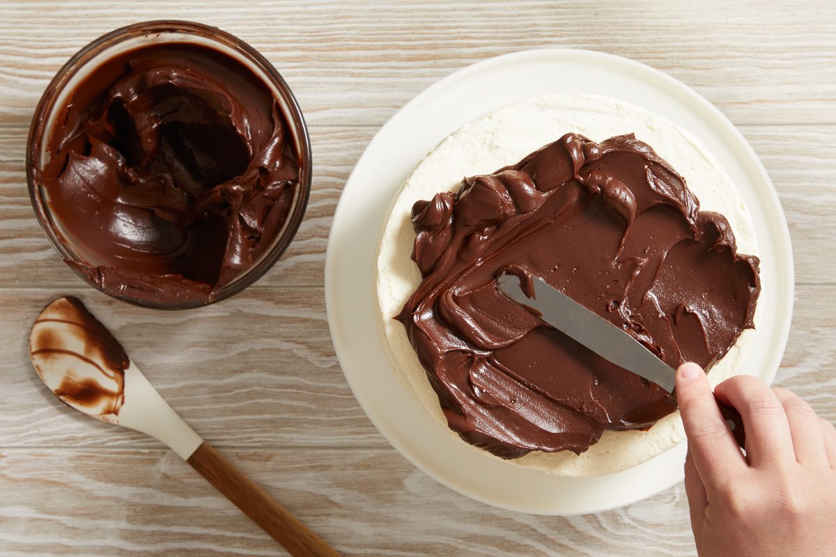 ganache being spread over top of cake