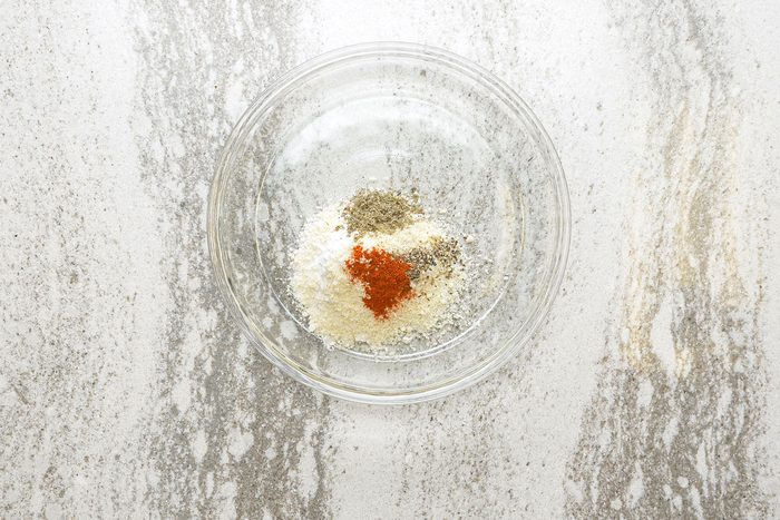 Flour, Parmesan cheese, sage, paprika and pepper in a shallow glass bowl.