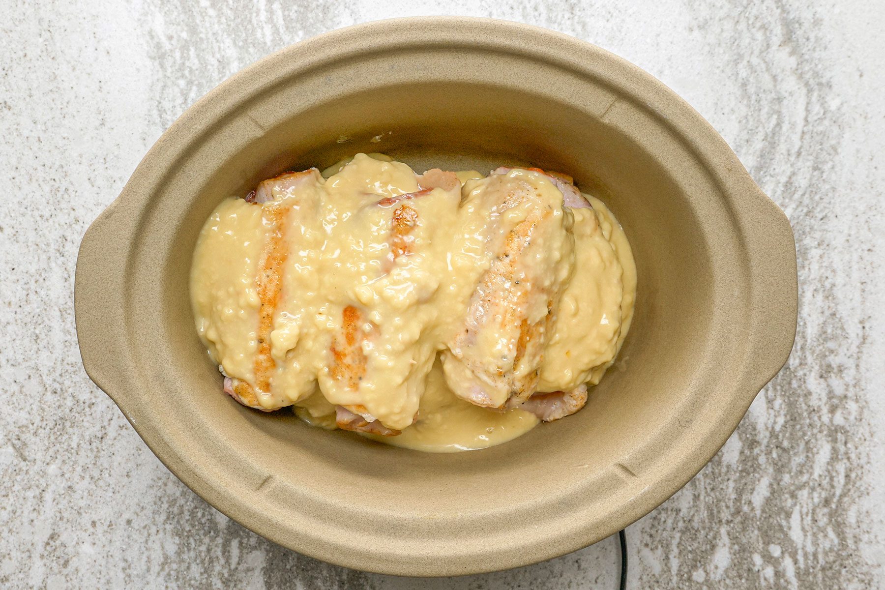 Pour the condensed soup and chicken broth mixture over the chicken rolls.