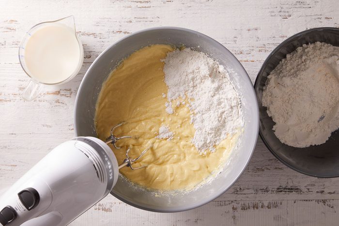 Whisking flour, pudding mix, cornstarch, baking powder and salt together in a bowl with a cup of milk on side.
