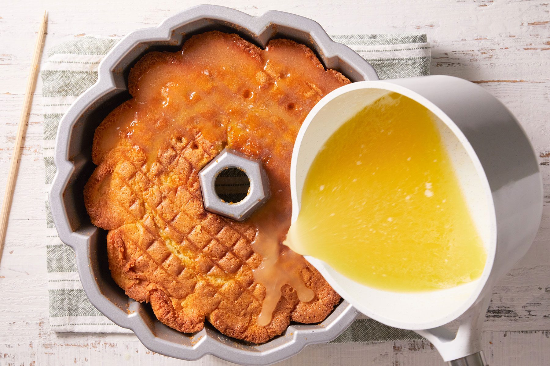 Pouring a syrup over the cake until all the syrup is absorbed.
