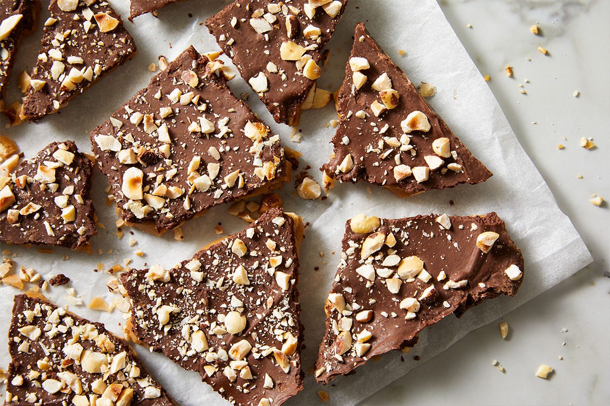 Overhead shot of Contest-Winning Hazelnut Toffee pieces scattered on parchment paper with visible chopped hazelnuts.