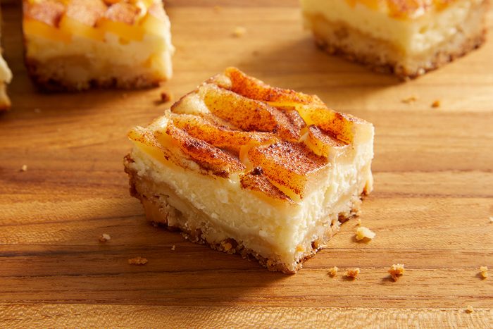 Close-up shot of sliced Pear Custard Bars showing creamy custard layers and caramelized pear topping on a wooden surface.