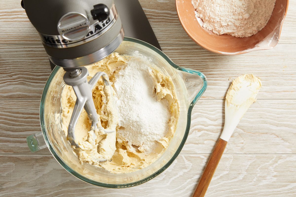 flour, baking soda and salt mixture being added to butter, vanilla and eggs mixture