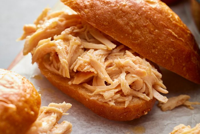 Close-up shot of slow-cooker shredded turkey sandwiches on a wooden board