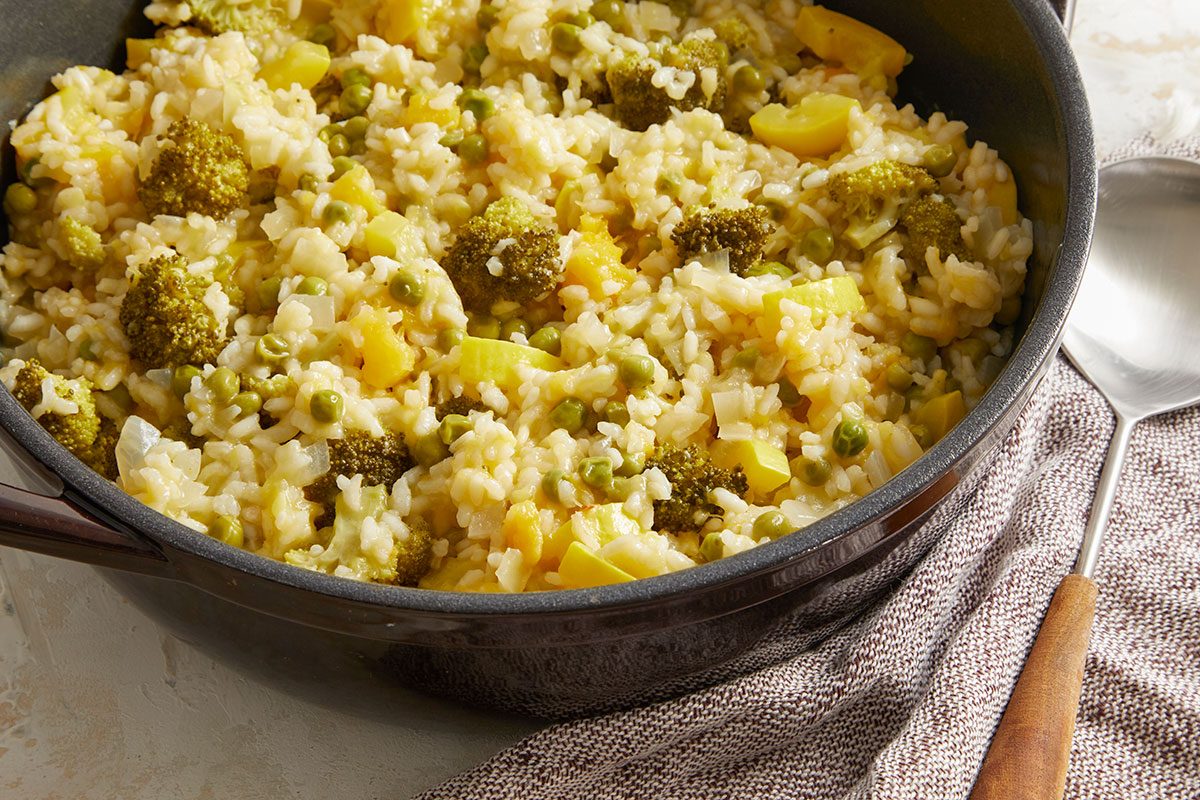 Overhead shot of the finished Vegetable Risotto in a pot, creamy and dotted with bright vegetables.