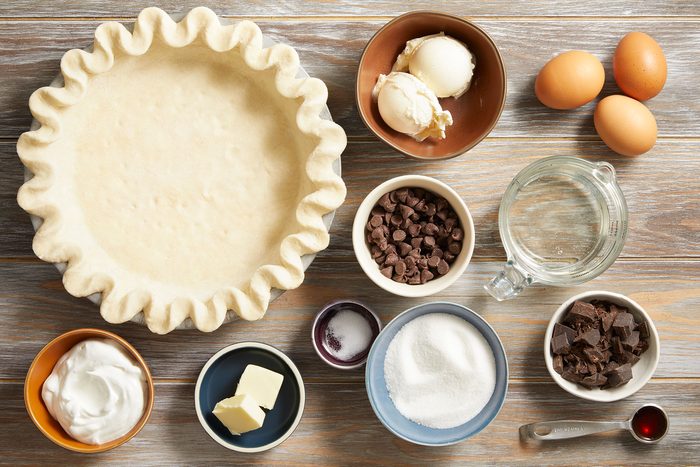 Ingredients for Brownie Pie in small plates and bowl on a wooden table.