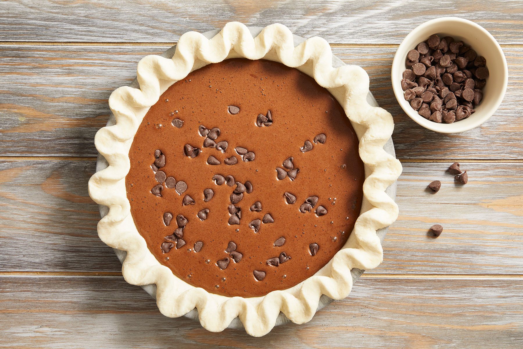 Pouring brownie filling into the pastry shell and Sprinkling the top with semisweet chocolate chips.