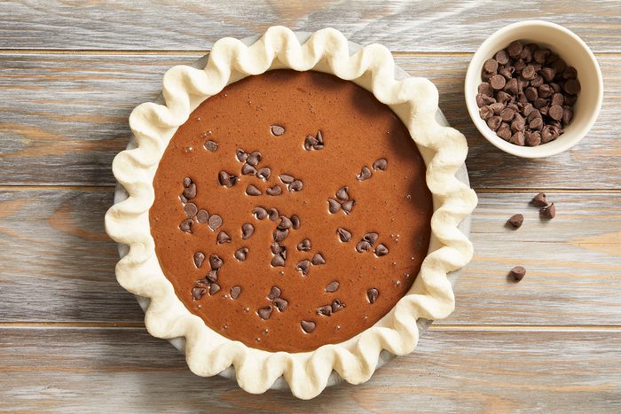 Pouring brownie filling into the pastry shell and Sprinkling the top with semisweet chocolate chips.