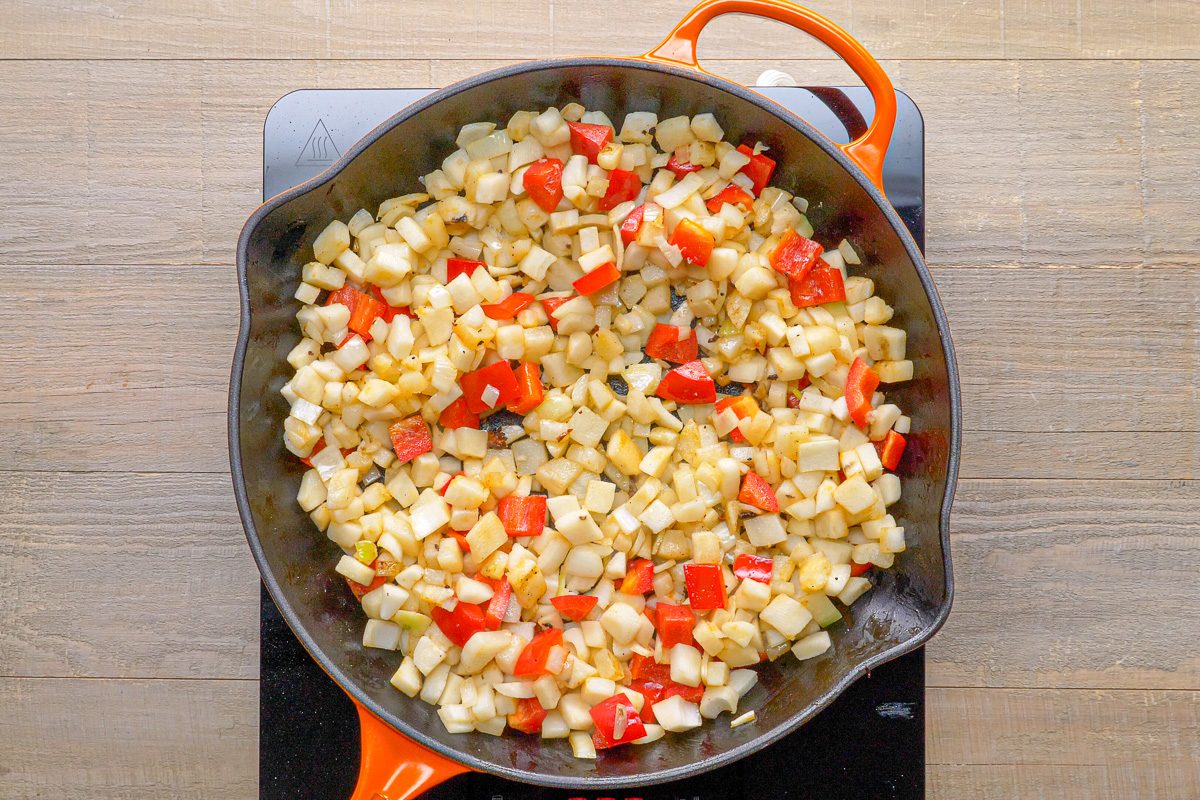 potatoes, onion and pepper being cooked in a skillet