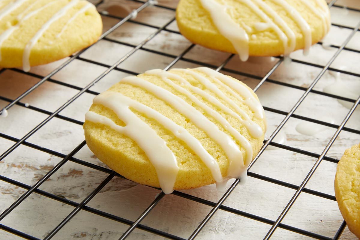 Close-up shot of a few Lemon Slice Sugar Cookies cooling on a wire rack, showing bright yellow glaze lines