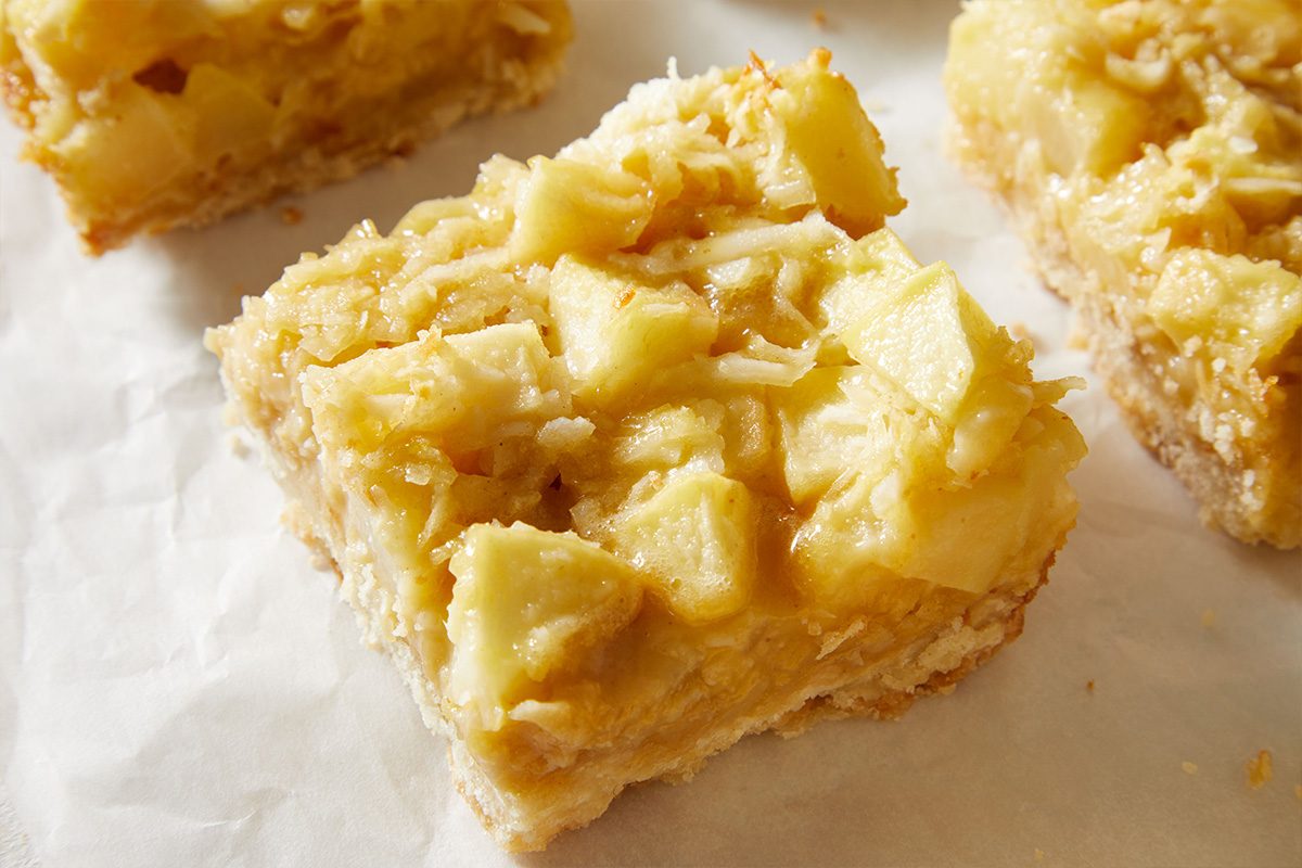 Close-up shot of a single Pear Bar Cookies piece showing tender fruit chunks and buttery crust texture on white parchment paper.