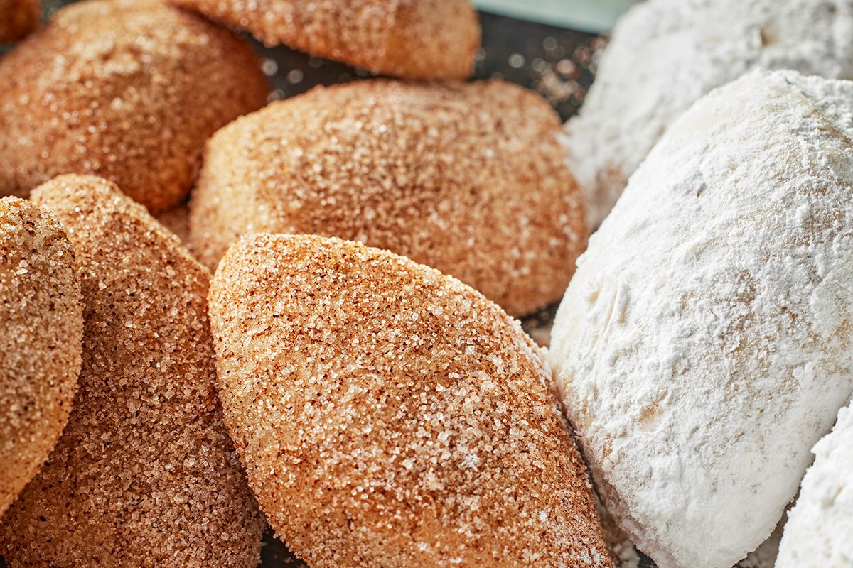Close-up of several pieces of kibbeh, a Middle Eastern dish, coated with breadcrumbs and one piece covered in flour, arranged closely together.