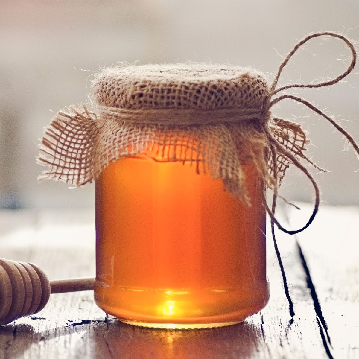 Golden honey with honey stick on wooden table