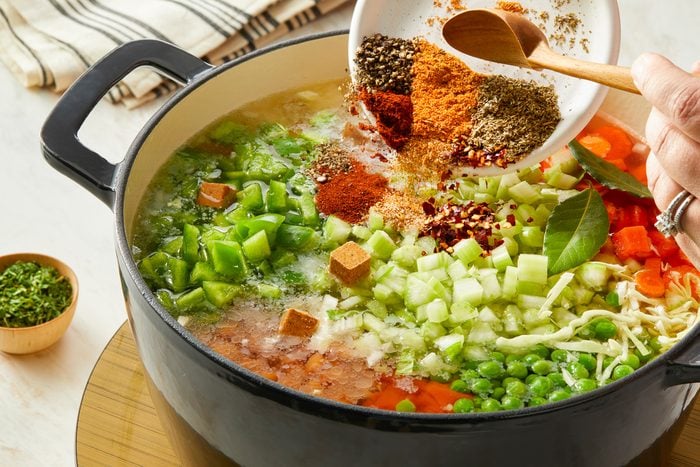 water, bouillon, canned tomatoes, pork and beans, condensed tomato soup, mushrooms, onion, green pepper, celery, carrots, potatoes, cabbage, frozen peas, dried parsley, Cajun seasoning, chili powder, Creole seasoning, pepper, red pepper flakes, Italian seasoning and bay leaf added to dutch oven