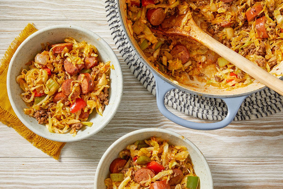 Overhead trend food photography of Dirty Cabbage served in bowls with sausage, ground beef, and seasoned cabbage.