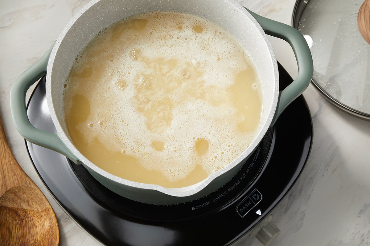 An overhead, horizontal step-by-step cooking image showing mushrooms, green onions, garlic, and fresh ginger sautéing in sesame oil inside a light-colored Dutch oven. This image captures the first stage of building flavor for Easy Dumpling Soup, highlighting the aromatic base before liquid ingredients are added.