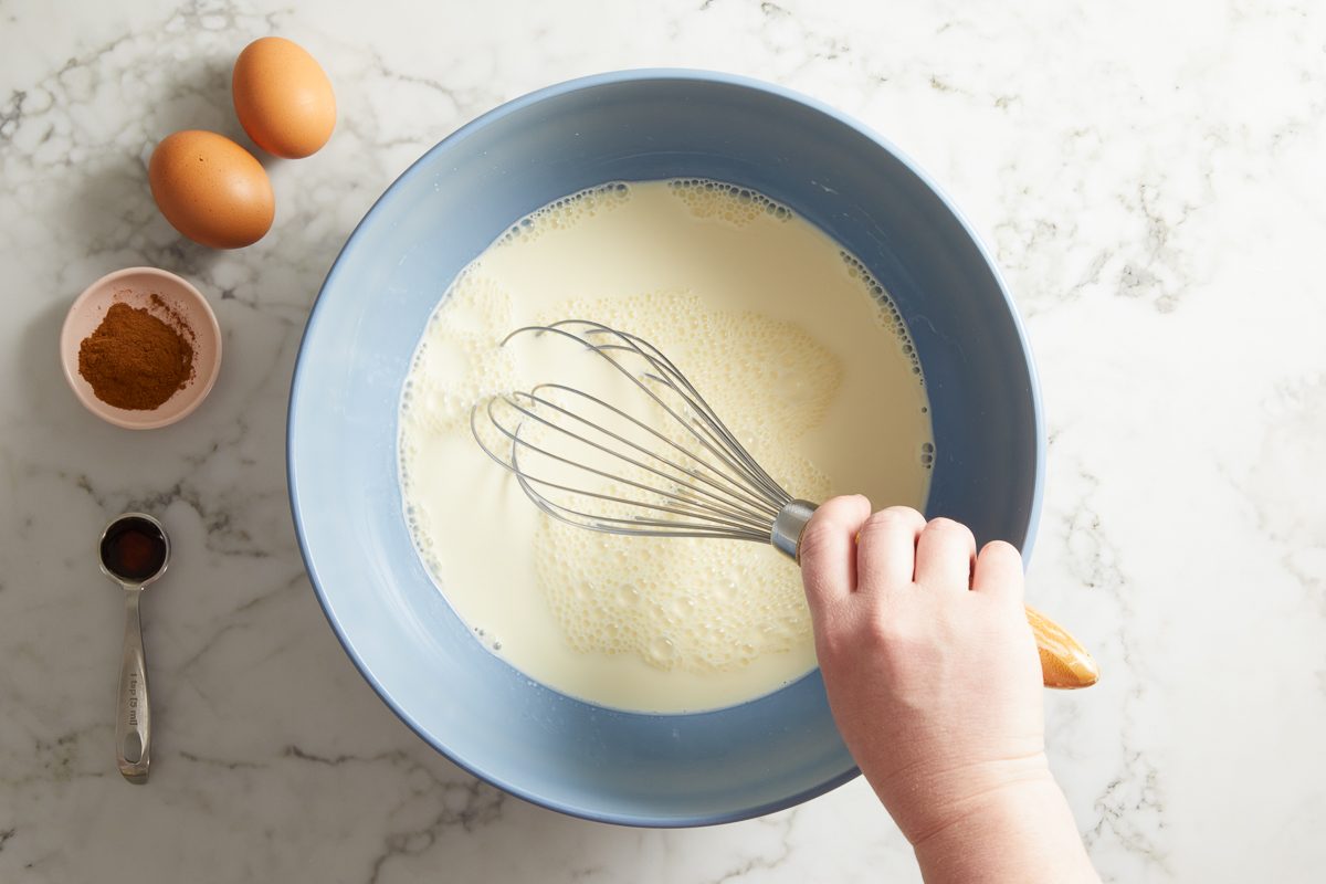half-and-half, milk, melted butter, maple syrup, eggs and egg yolks, cinnamon, vanilla and salt being whisked together in a large bowl