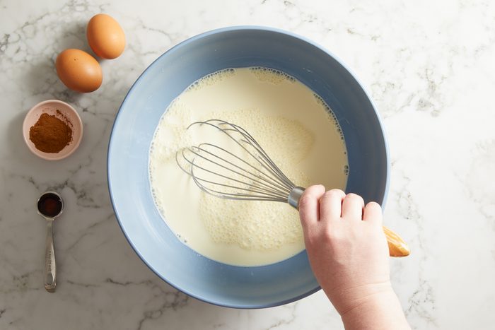 half-and-half, milk, melted butter, maple syrup, eggs and egg yolks, cinnamon, vanilla and salt being whisked together in a large bowl