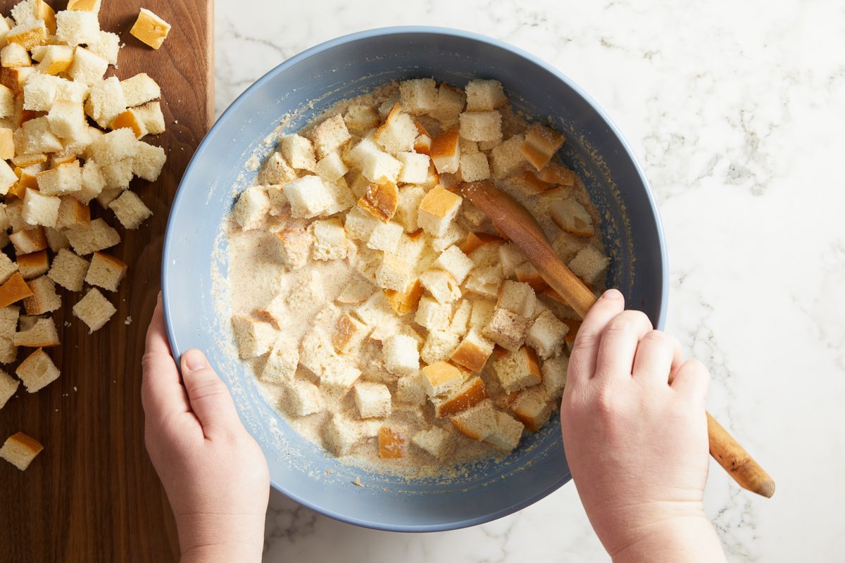 bread cubes being stirred in with wet mixture