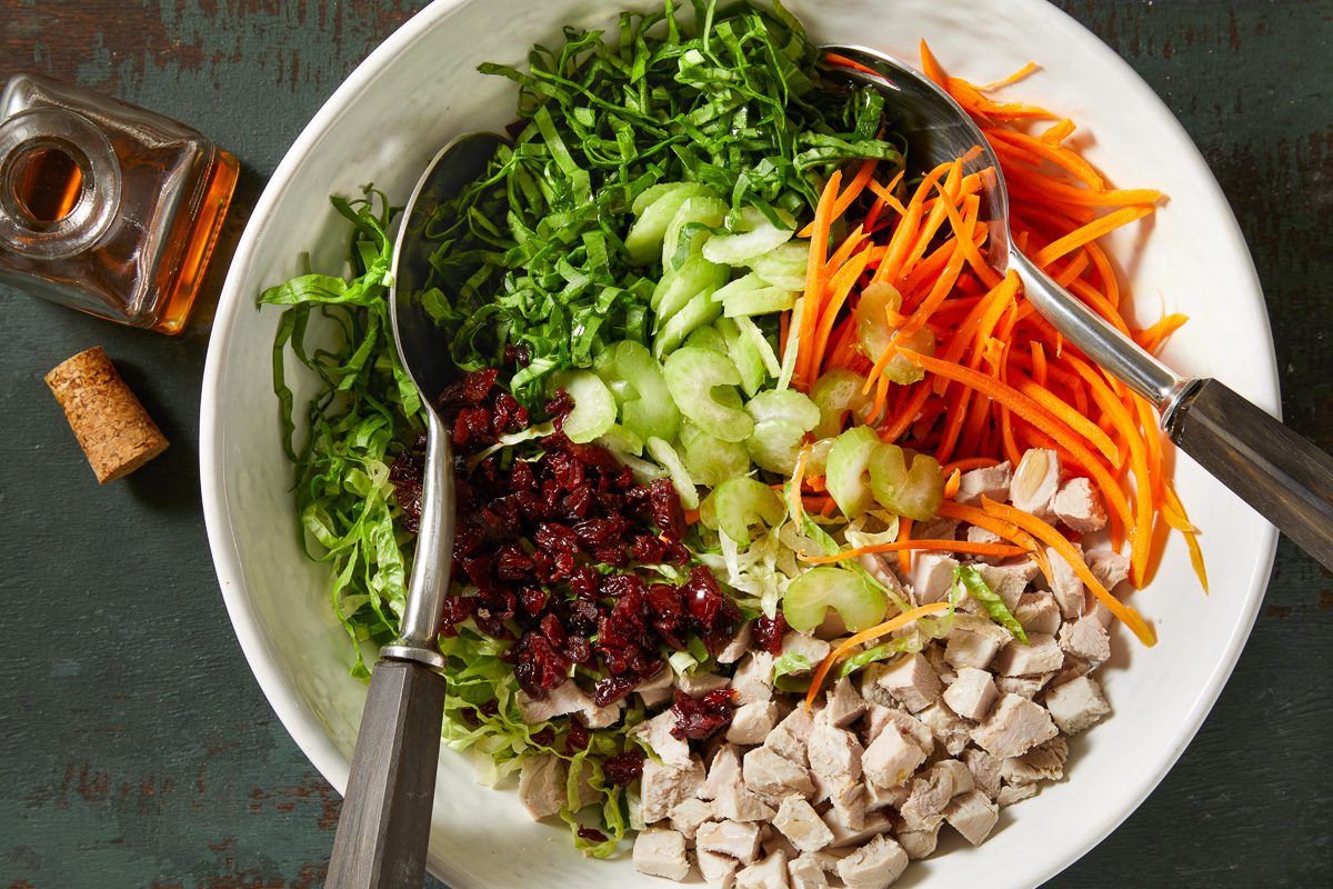 romaine, spinach, carrot, celery, dried cherries and pork in a large bowl