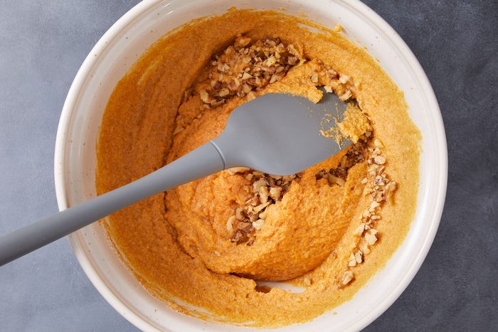 Gently folding walnuts into Keto Pumpkin Muffins mixture.