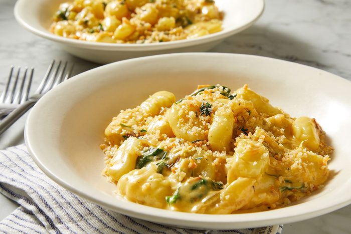 An overhead, horizontal image featuring a plated serving of Million-Dollar Gnocchi garnished with thyme and crispy breadcrumb topping.