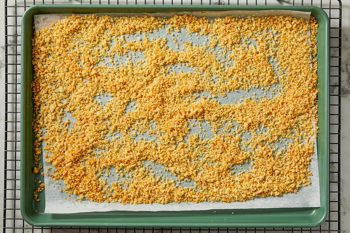 An overhead, horizontal step-by-step image of a prepared breadcrumb topping evenly spread in a baking dish, ready to be baked for Million-Dollar Gnocchi.