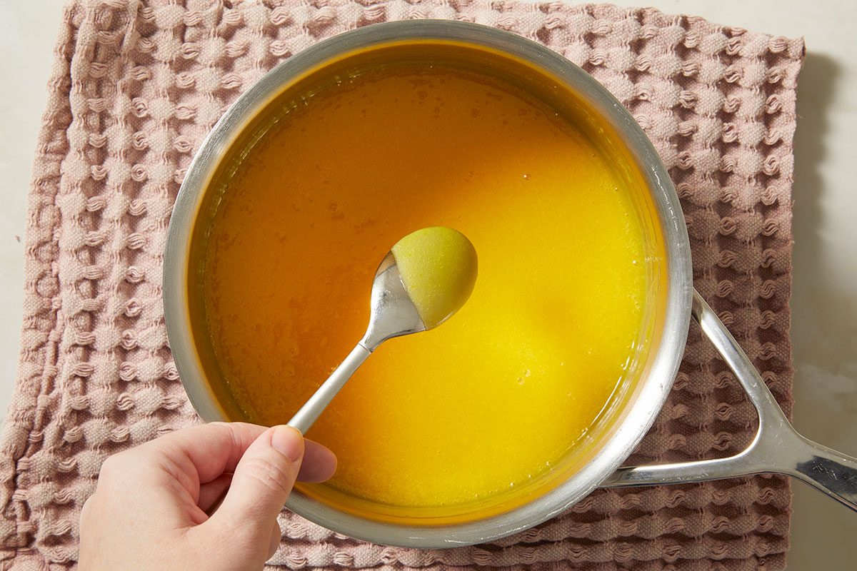 Overhead, horizontal step-by-step image of a smooth, glossy passion fruit filling finished in a saucepan, ready to be poured into the prepared tart crust.