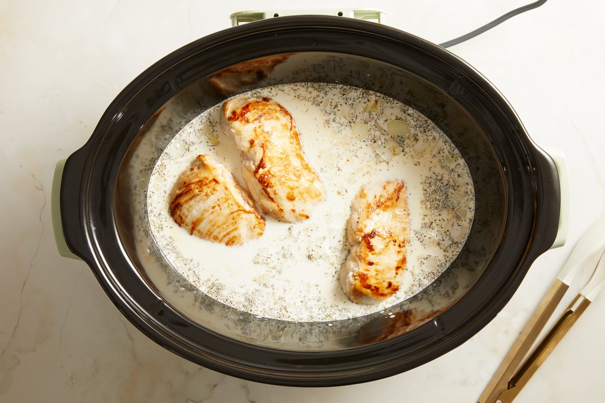 chicken being slow cooked in broth and cream mixture