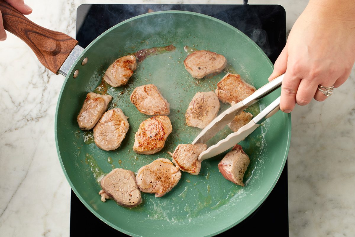 sliced tenderloin being cooked in a skillet
