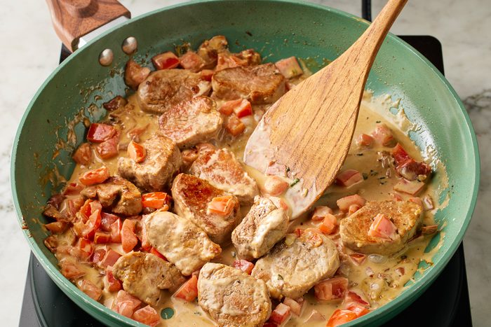 chopped tomatoes and pork added to skillet with sauce