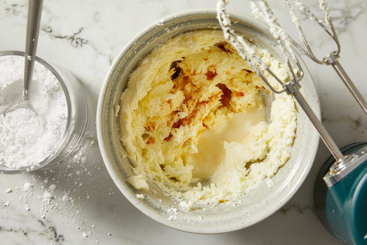 Overhead view of cream cheese frosting being mixed in a bowl, showing a smooth and creamy texture.