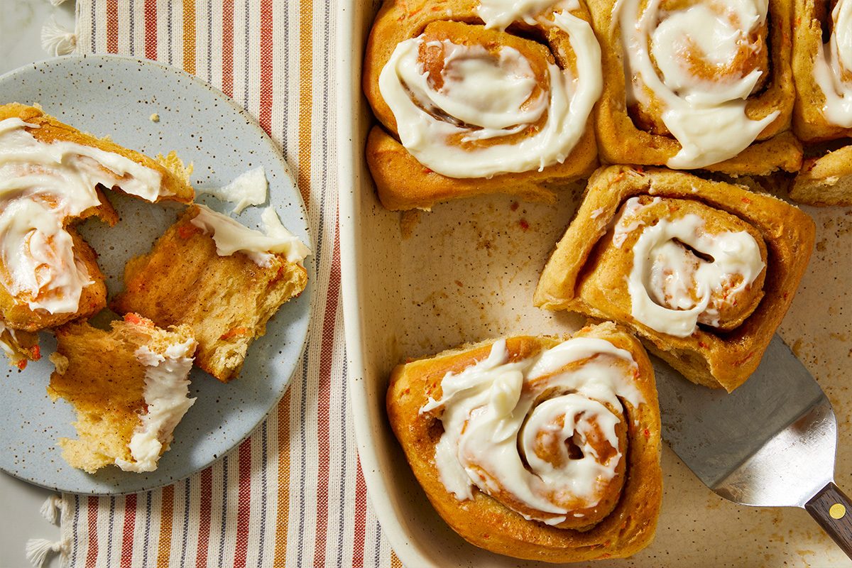 Overhead view of carrot cake cinnamon rolls served and partially pulled apart, highlighting the soft interior and creamy frosting.