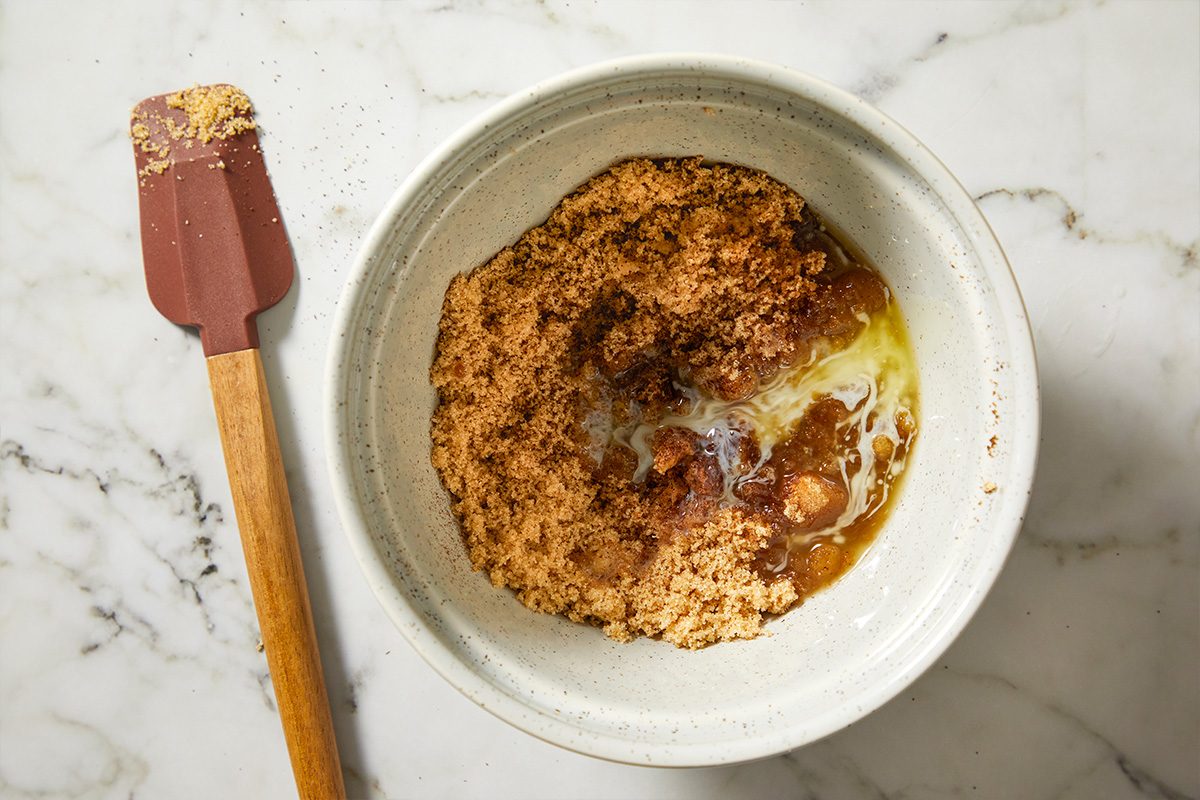 Overhead view of cinnamon roll filling ingredients mixed in a small bowl, featuring brown sugar, spices, and butter.