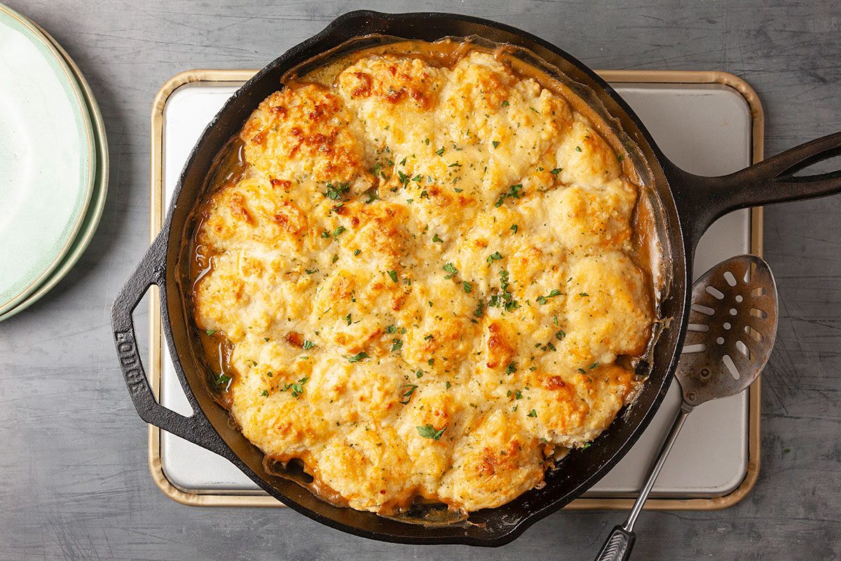 Overhead horizontal image of a fully baked Cheddar Bay Chicken Pot Pie resting on a cooling rack, highlighting even browning and texture across the biscuit topping.