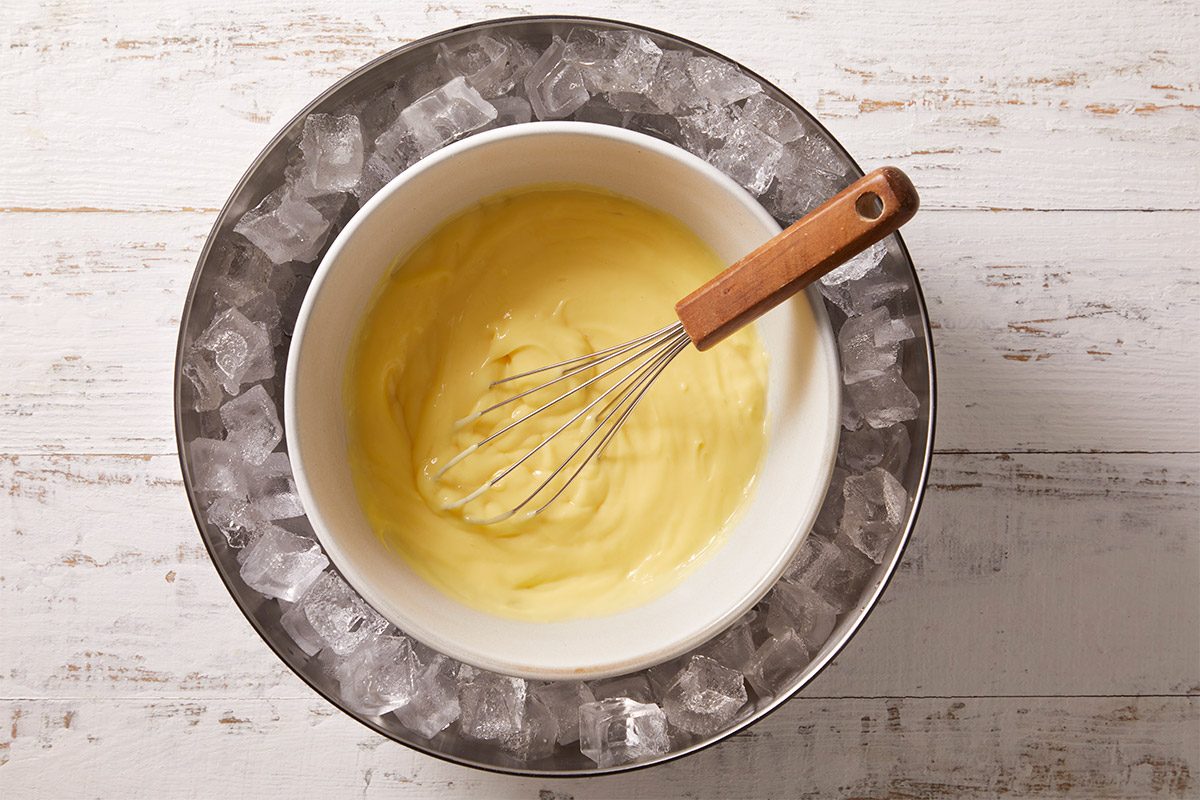 A horizontal overhead image of finished pastry cream whisked until smooth and creamy in a mixing bowl. The custard is prepared as a filling for Crème Brûlée Doughnuts.
