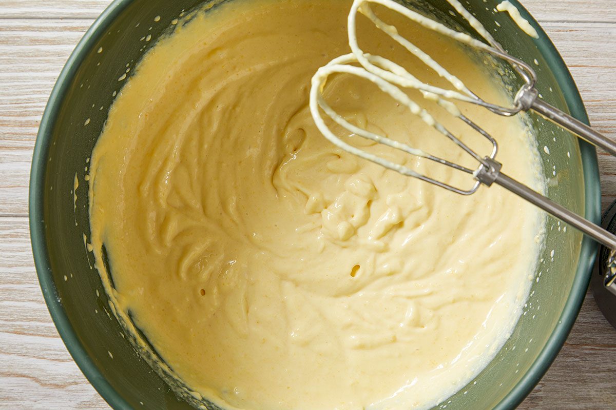 Top-down image of a creamy filling mixture being whisked in a bowl, creating the Irish cream layer used in the poke cake recipe.