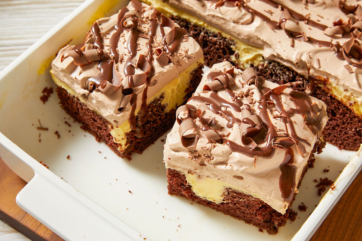 Top-down image of sliced Irish cream poke cake squares arranged in a baking dish, highlighting the layered interior and decorative topping.